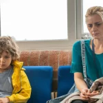 Child and woman sitting in a waiting room, looking worried, representing family counseling, child mental health, parenting support, or social services assistance. A still from the short film Majority.