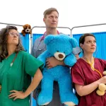 Three healthcare professionals stand with teddy bears and a large blue teddy bear in a pediatric medical setting, illustrating children’s healthcare, medical examinations, and pediatric care.